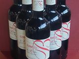 six bottles of wine are lined up in a row on a red surface