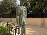 a statue of a man holding a hat on a pedestal