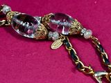 purple glass beaded necklace on a pink cloth with a gold chain