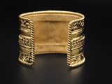 a close up of a gold bracelet on a black surface