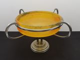 a yellow bowl on a metal stand on a black table