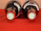 two bottles of wine sitting on a red cloth