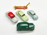 quatre petites voitures et un avion posés sur une surface blanche