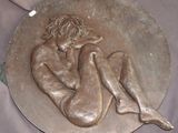 une plaque en bronze représentant une femme assise sur un plateau