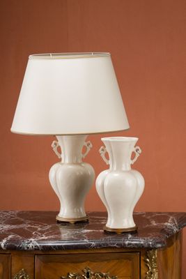deux vases blancs posés sur une table sur laquelle se trouve une lampe