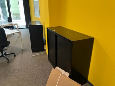une armoire noire dans un coin d'une pièce aux murs jaunes