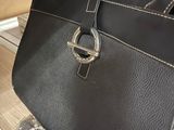 black leather handbag with a silver buckle on top of a stack of books