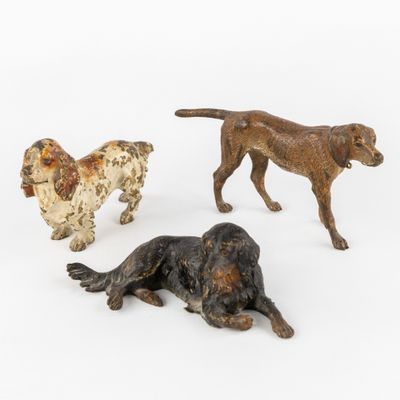trois figurines de chiens posées sur une surface blanche, sur fond blanc