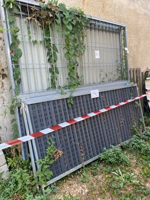 une clôture qui a été renversée et sur laquelle est enroulé un ruban rouge et blanc