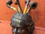 une statue d'un homme avec une tête pleine de têtes de pipes