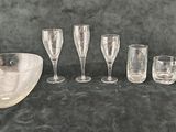 several glasses and a bowl on a table with a black background