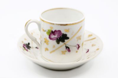 a white cup and saucer with purple flowers on it