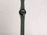 the watch is sitting on a white surface with a green strap