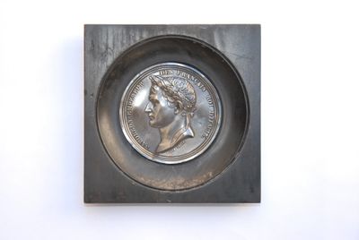 a close up of a coin in a metal tray on a white surface