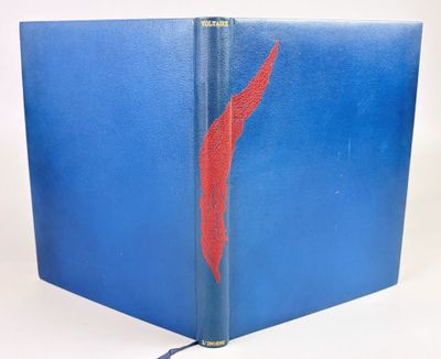 un livre bleu ouvert, avec une plume rouge sur la couverture