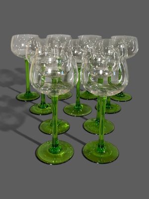 six verres à vin verts sont alignés sur une surface grise