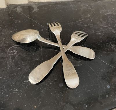 quatre cuillères et deux fourchettes sur une table noire