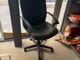 a black office chair sitting in front of a glass door