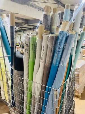 many rolls of fabric in a wire basket on the floor