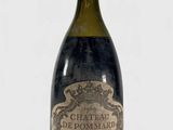 une vieille bouteille de vin posée sur une table blanche