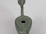 a green vase with a bird on it on a white surface