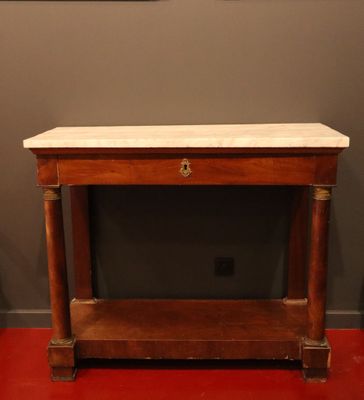une vieille table en bois avec un plateau en marbre, posée sur un sol rouge