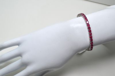 une main de mannequin blanche à laquelle est attaché un bracelet rouge
