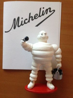 une figurine représentant un homme tenant une bouteille de vin devant une pancarte sur laquelle est écrit « Michel »