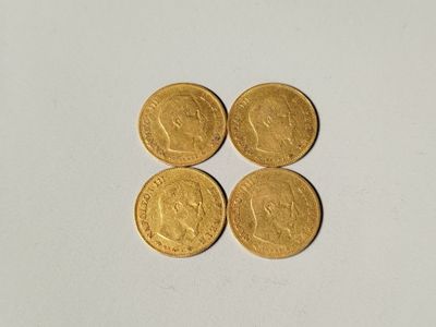 quatre pièces d'or superposées sur une surface blanche