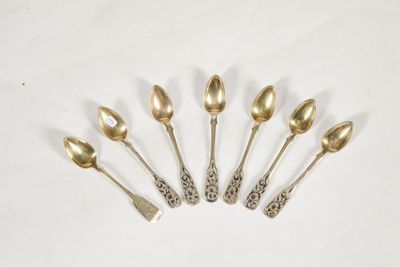 six cuillères et un repose-cuillère alignés sur une surface blanche