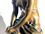 a bronze statue of a woman sitting on a rock