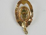 an image of a gold broochle with a flower on it