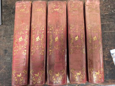 six livres rouges ornés de motifs dorés, posés sur une table