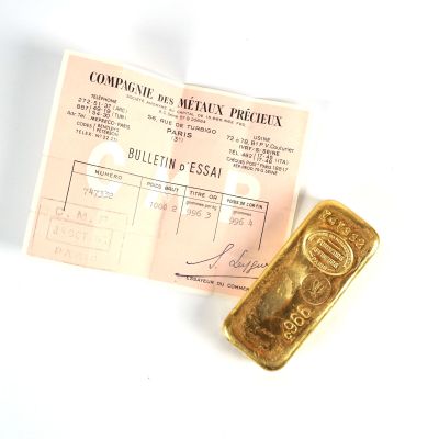 un lingot d'or posé à côté d'une feuille de papier sur une table