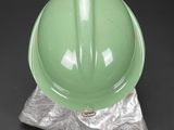 a green helmet sitting on top of a piece of metal