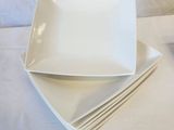 several white square plates stacked on top of each other on a couch