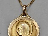 a close up of a gold necklace with a woman ' s face on it