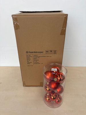 une boîte de décorations rouges posée sur une table à côté d'une boîte de décorations rouges
