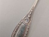 an antique silver spoon on a white surface with a silver handle