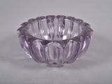 un bol en verre violet posé sur une table blanche, sur fond blanc