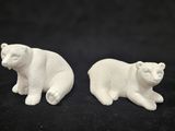 pair of white ceramic polar bear figurines on a black background