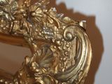 a mirror that has a gold frame with flowers on it