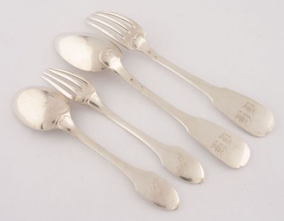 quatre cuillères et une fourchette en argent sur une surface blanche