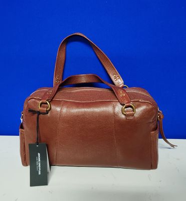 un sac à main marron muni d'une étiquette, posé sur une table