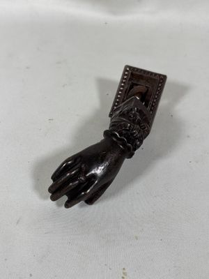 une image représentant une main en bois tenant un objet métallique sur une surface blanche