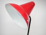 an image of a red lamp on a black stand against a white wall