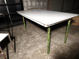 a white table with green legs in the middle of a room