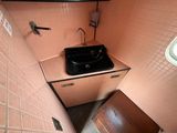 a black sink in the corner of a pink tiled bathroom