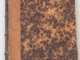 un vieux livre à la couverture brune posé sur une surface blanche
