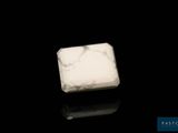 bloc de marbre blanc posé sur une surface noire, avec un fond noir